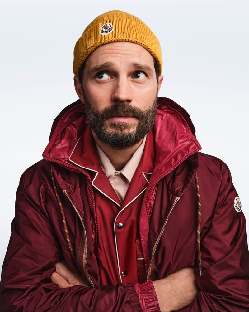 Jamie crosses his arms in a mustard Moncler beanie and a burgundy jacket and pajama-style shirt