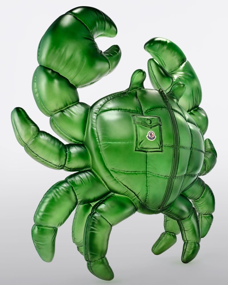 A metallic green Moncler puffer crab with raised claws, a zipper, and a Moncler logo patch