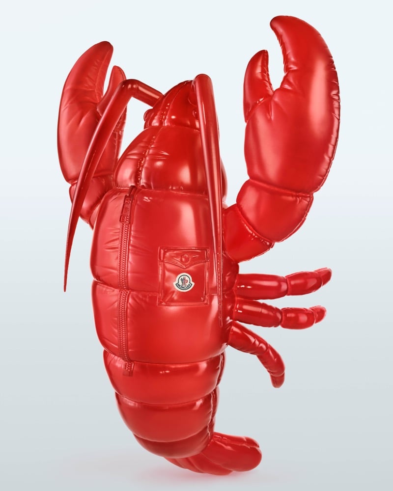A glossy red Moncler puffer lobster with raised claws, a zipper, and a Moncler logo patch