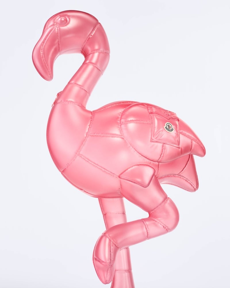 A metallic pink Moncler puffer flamingo with a curved neck and a Moncler logo patch