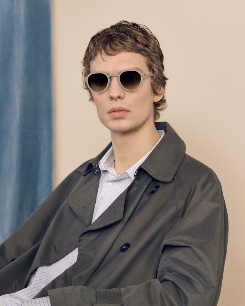 Leon Dame wears MYKITA x RIMOWA sunglasses with a trench coat over a striped shirt