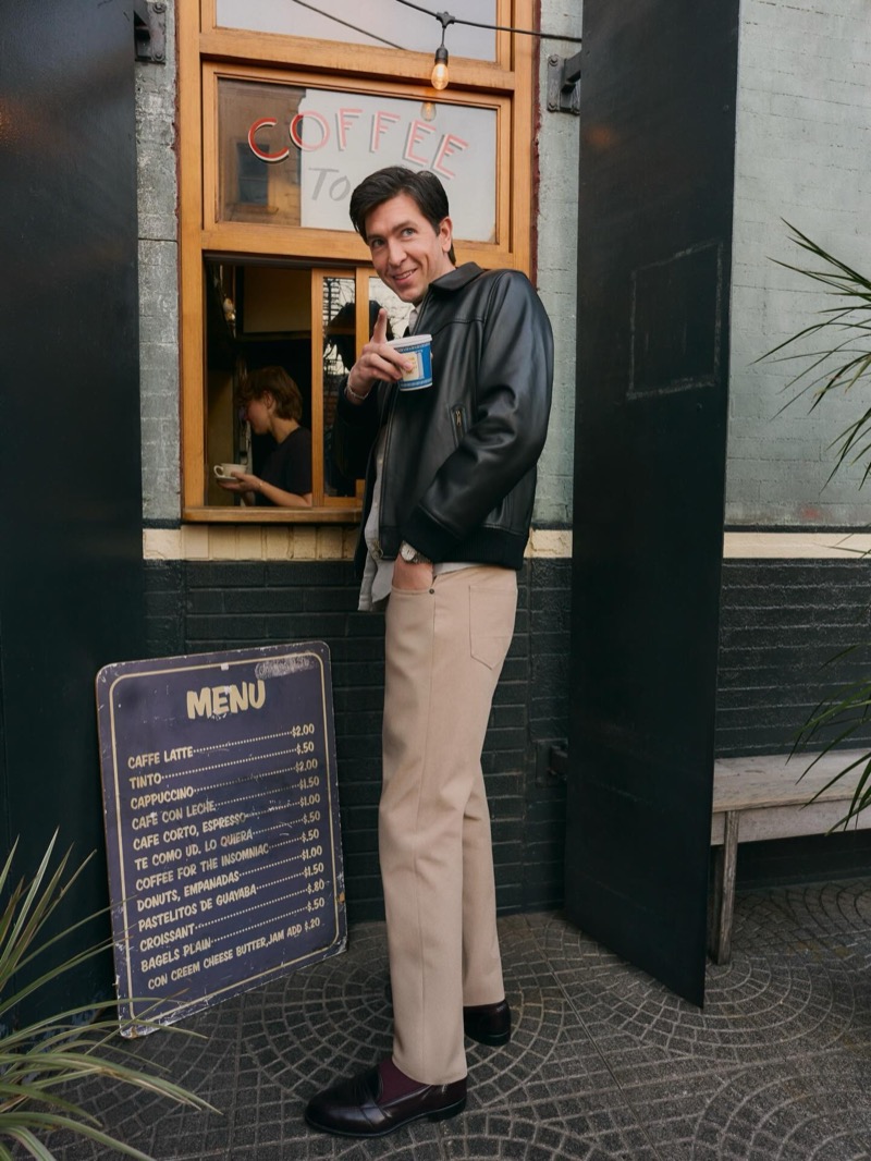 Braun stands at a coffee shop window in a leather jacket and Bonobos chinos
