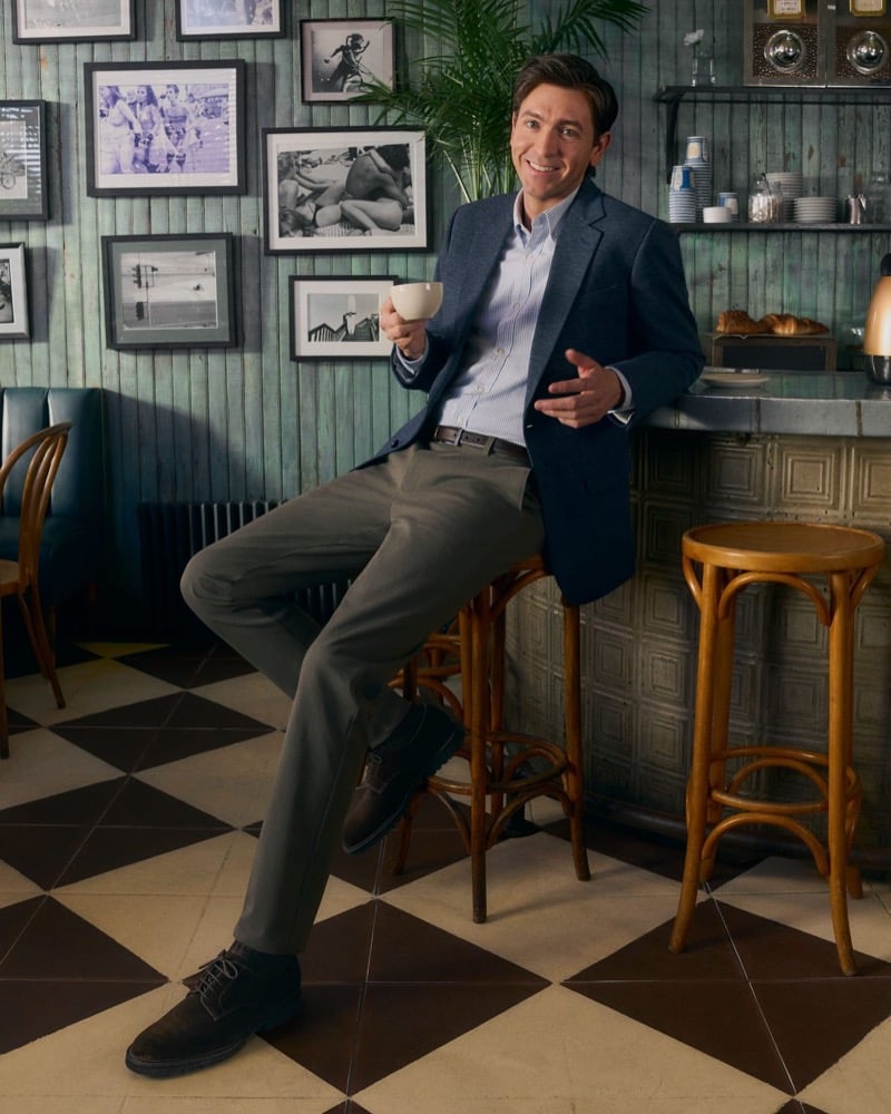Braun sits on a stool wearing soft tailoring and Bonobos chinos