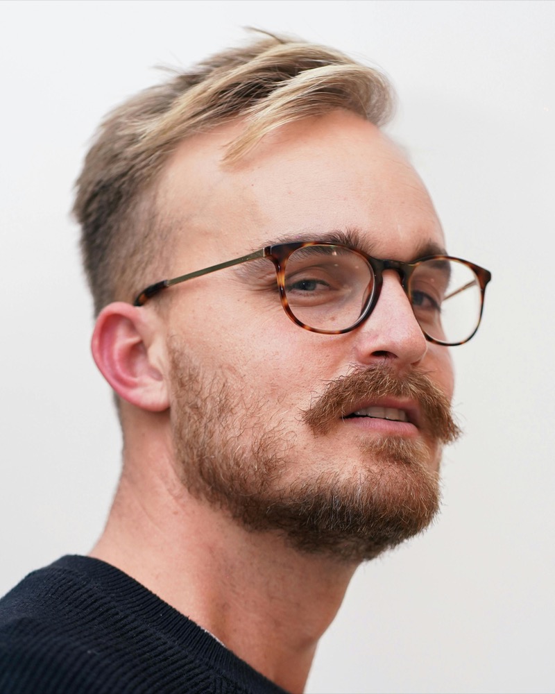 Man wearing oval tortoiseshell glasses with a white shirt