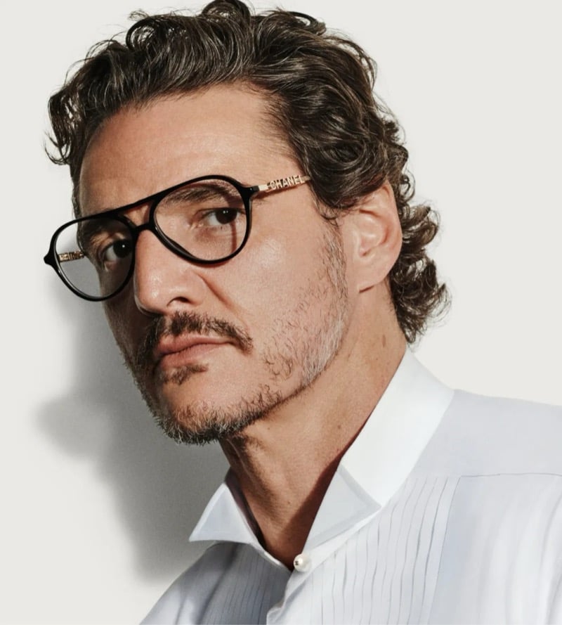 Pascal wears Chanel black pilot eyeglasses with gold CHANEL lettering along the arms, paired with a white pintuck evening shirt