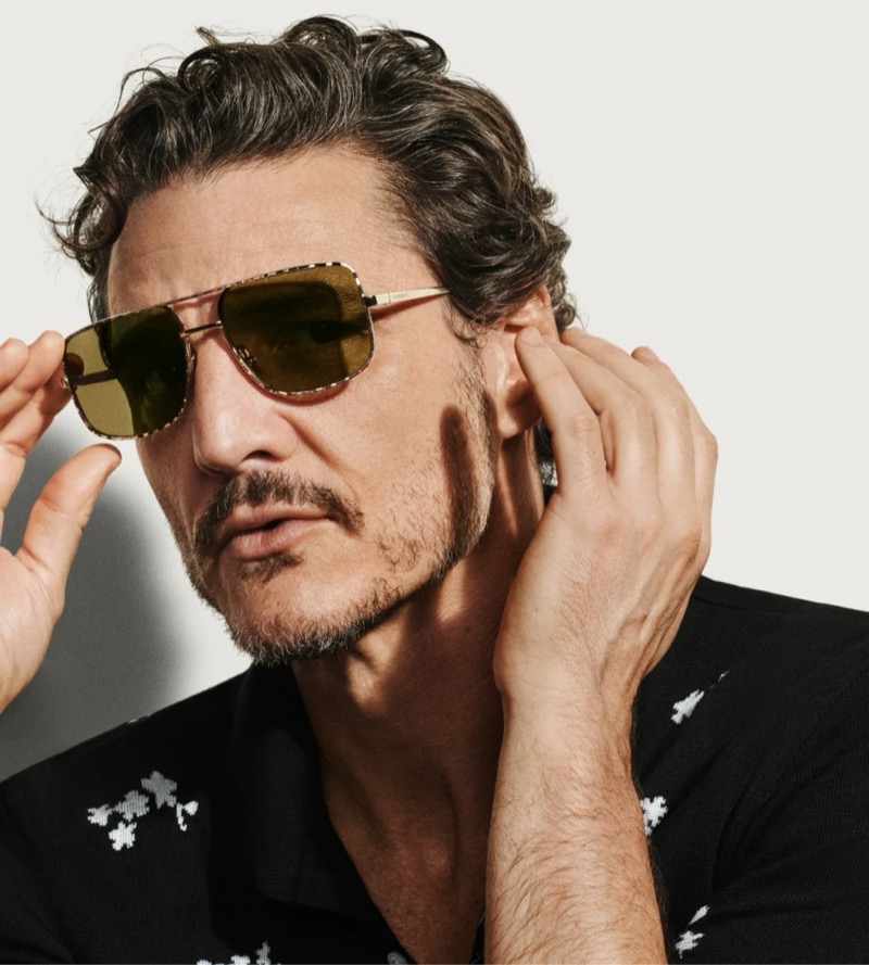Pascal adjusts Chanel light gold pilot sunglasses with a metal frame and tinted lenses, paired with a black floral intarsia polo