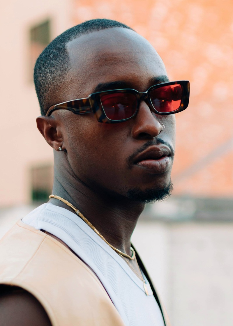 Man wearing rectangular tortoiseshell sunglasses with red-tinted lenses