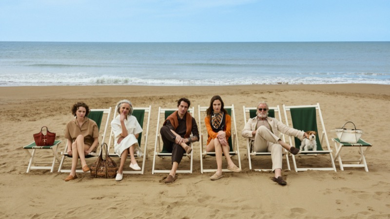 A cast of five in Tod's summer 2026 lounges in green folding chairs on the beach at Forte dei Marmi with Gomminos and leather bags