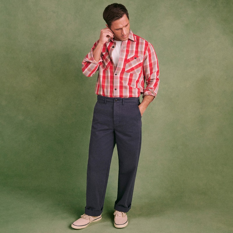 Model wears the Wallace & Barnes Selvedge Officer Chino Pant in navy with a red plaid shirt and sneakers