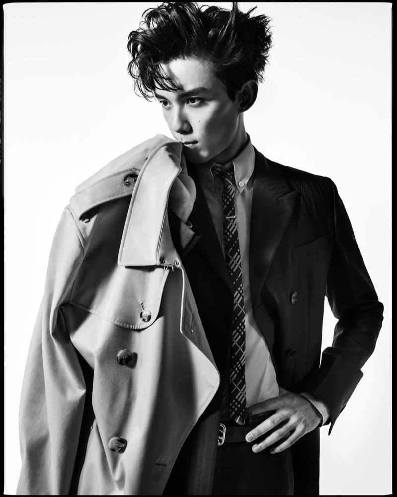Wu Lei drapes a Burberry Kensington trench over one shoulder of a dark suit with a check tie