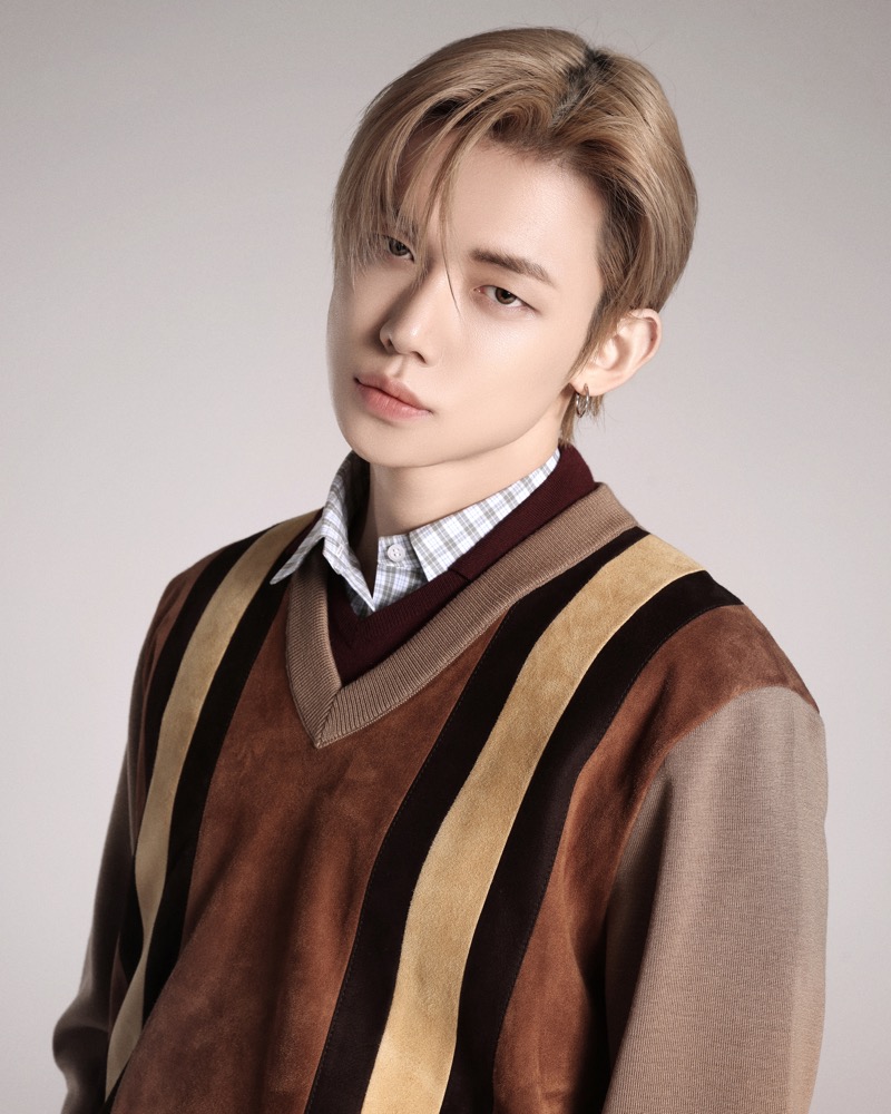 Yeonjun in a close-up portrait wearing a striped suede Miu Miu V-neck layered over a checked button-down shirt, with a small hoop earring, as a Miu Miu Friend of the House