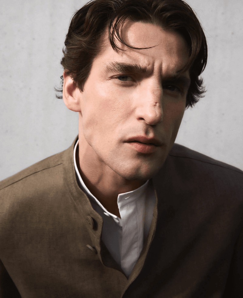 Close portrait of Anatol in a taupe Adolfo Dominguez Mandarin-collar jacket layered over a white Mandarin-collar shirt