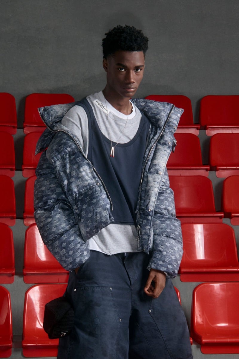Nehemiah Kargbo wears a Dsquared2 monogram cropped puffer over a gray tee and navy athletic tank with slouchy navy carpenter trousers
