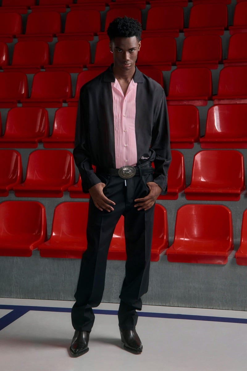 Nehemiah Kargbo wears a black and pink pleated-bib shirt with black wool trousers, a silver concho belt, and black Western boots