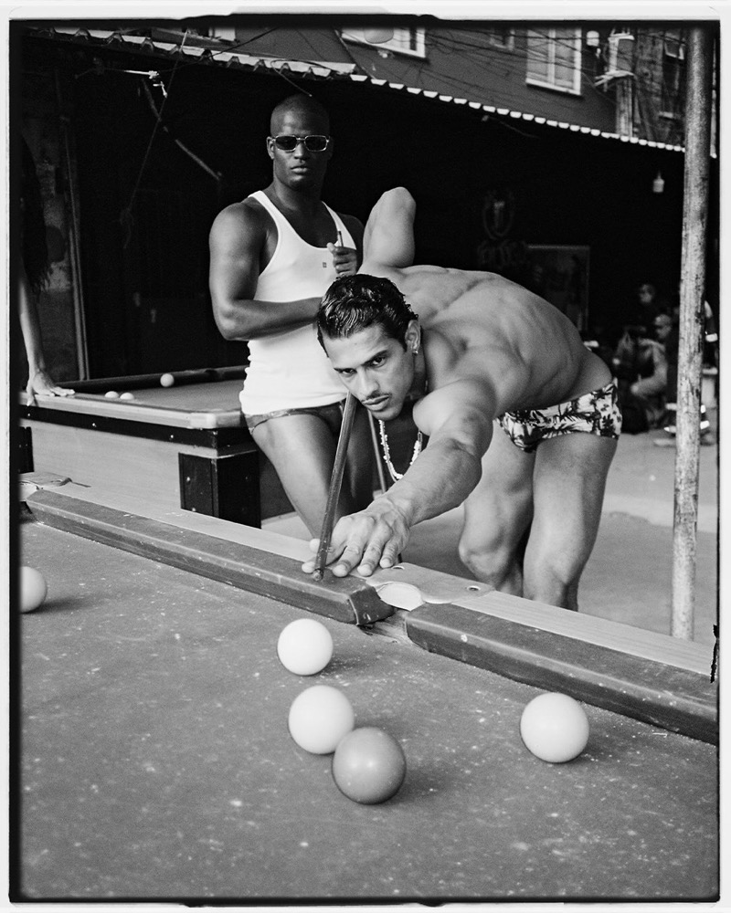 Two men at an outdoor Rio pool table in Dsquared2 swimwear, photographed in black and white