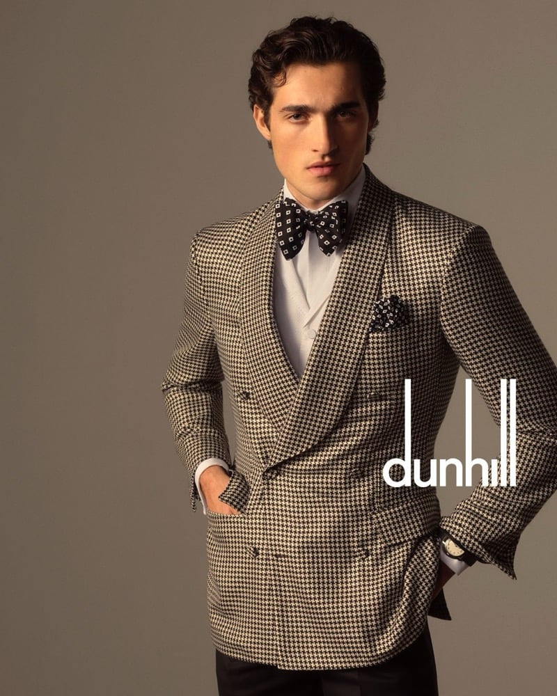 Adam wears a black and cream houndstooth double-breasted evening jacket over a white shirt with a geometric bow tie and matching pocket square
