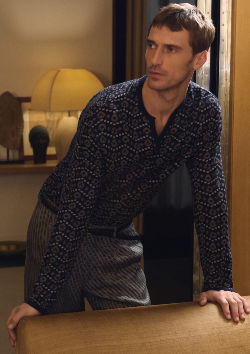 Clément leans on a sofa back at Giorgio Armani's residence in a navy diamond-printed silk shirt with gray pinstriped trousers