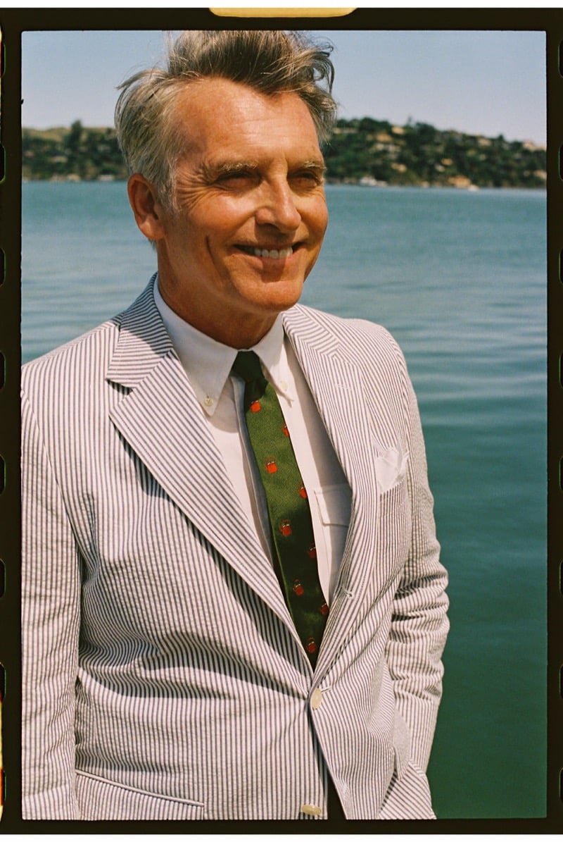 John Pearson wears a blue and white seersucker suit over a white button-down with a green tie embroidered with lobster motifs and a white pocket square at the harbor