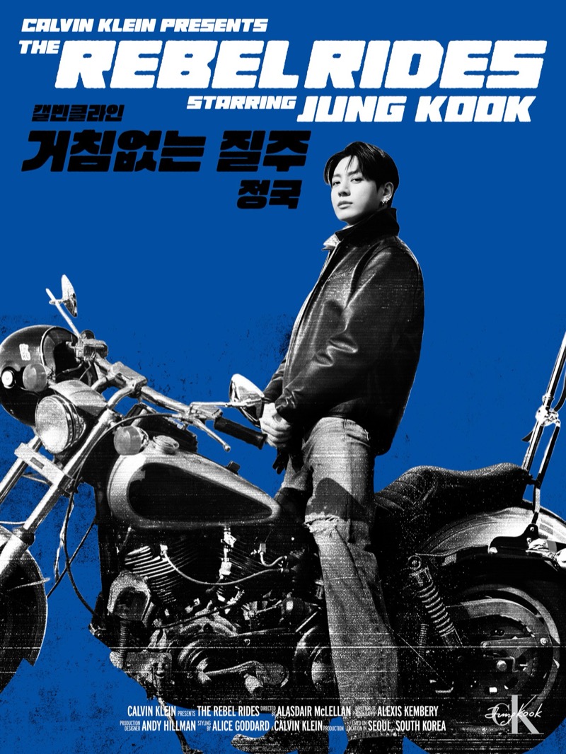 Blue-ground Calvin Klein campaign poster of Jung Kook standing beside a motorcycle in a black leather biker jacket and light denim jeans, the CKJK signature at the bottom
