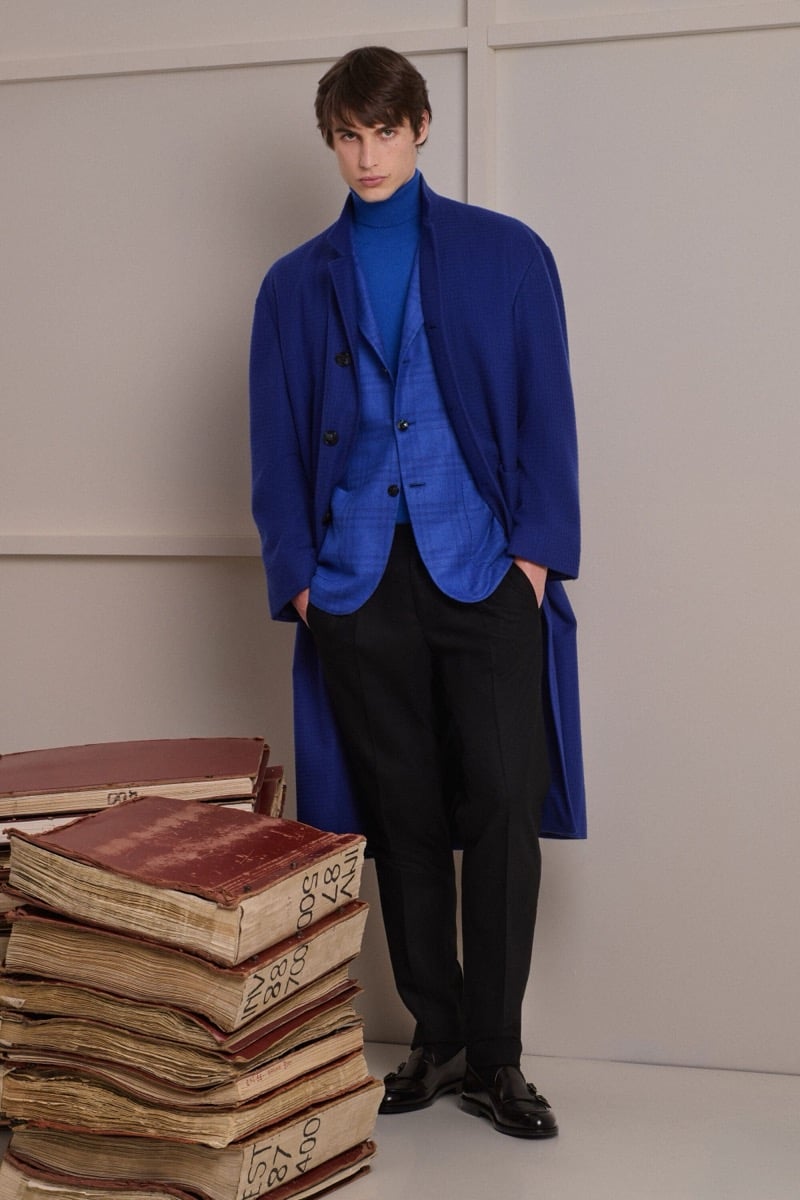 Unai Bartra wears a deep cobalt blue single-breasted overcoat over a cobalt jacket and cobalt turtleneck with black trousers and black loafers
