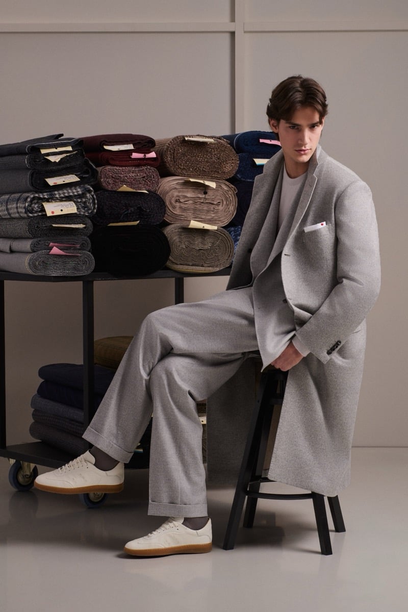 Unai Bartra wears a light gray single-breasted overcoat and matching trousers over an ivory tee with white sneakers