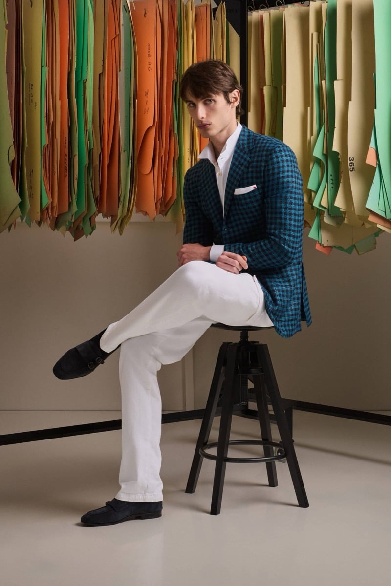 Unai Bartra wears a teal gingham check blazer over a white shirt with ivory trousers and navy suede loafers