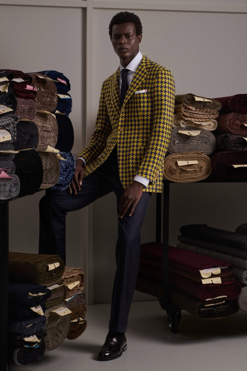 Mohammed Abubakar wears a mustard and navy houndstooth blazer over a white shirt with a black tie and charcoal trousers