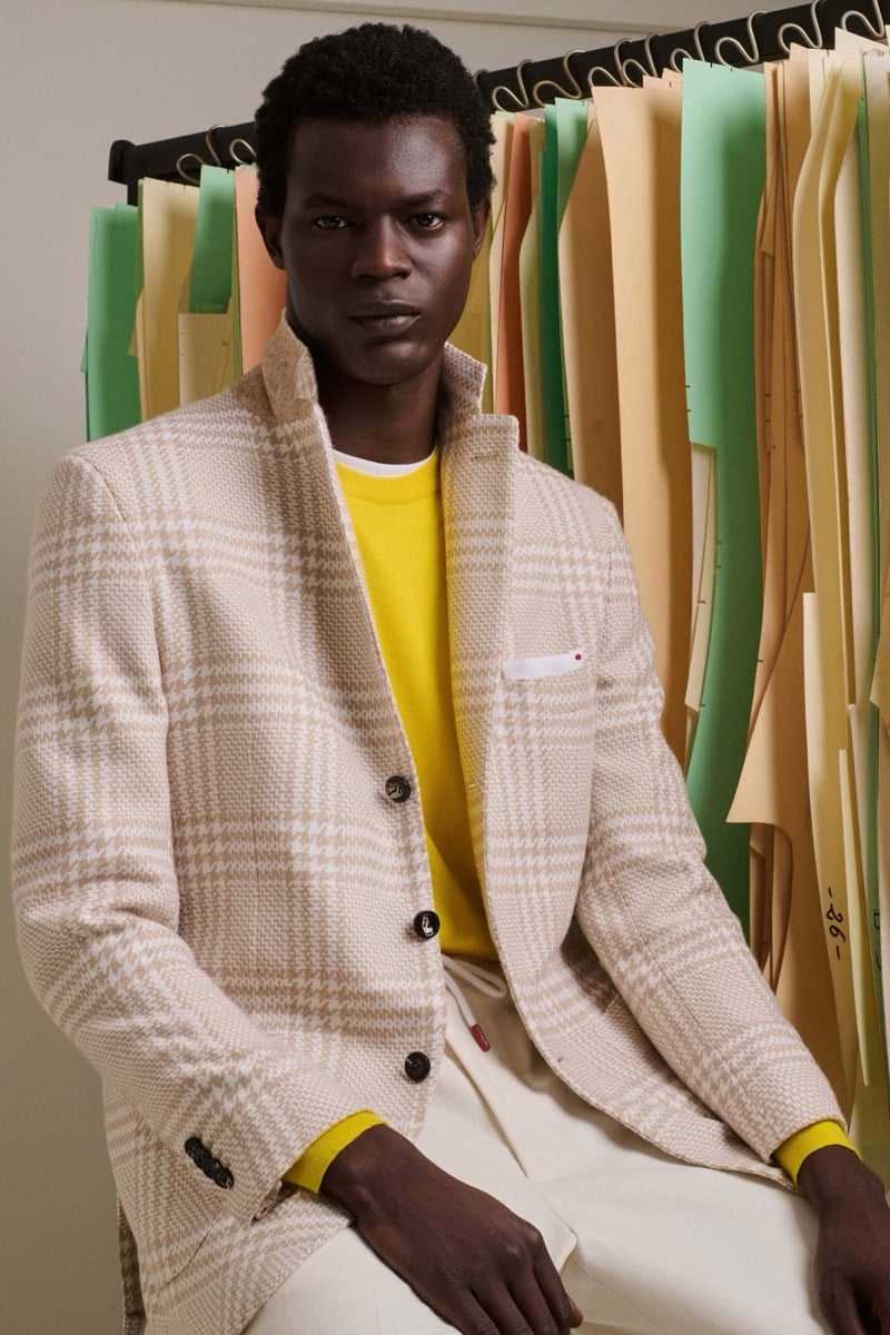 Mohammed Abubakar wears a cream and oatmeal houndstooth blazer over a bright yellow crewneck sweater with ivory trousers