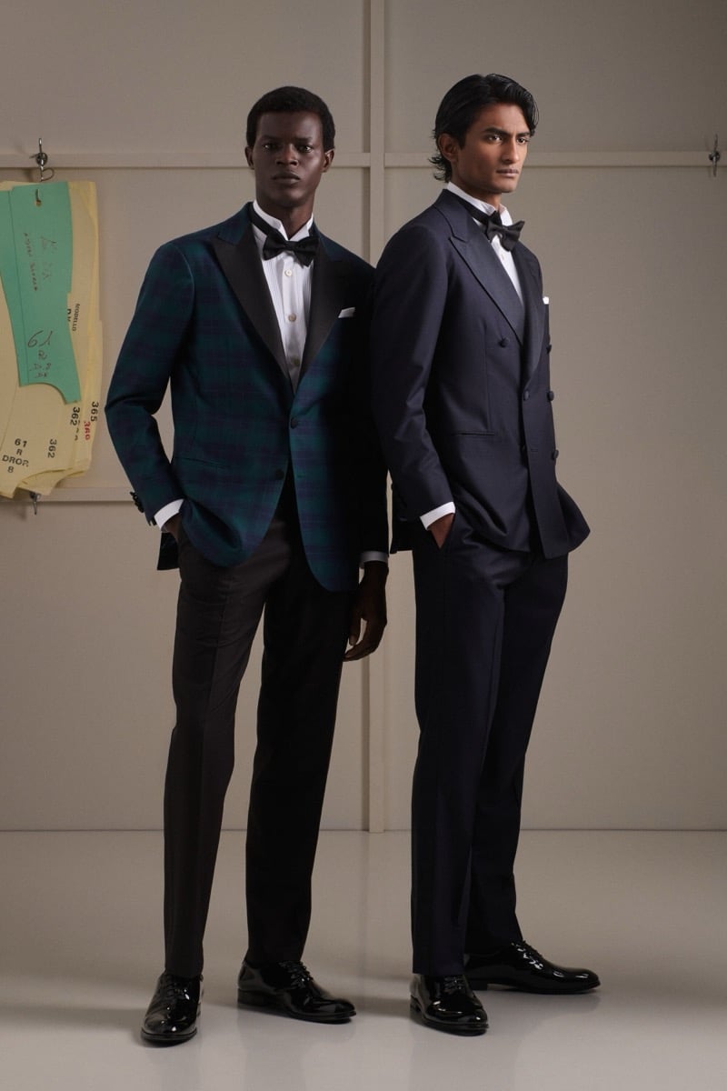 Mohammed Abubakar wears a green and navy blackwatch tartan dinner jacket with a black bow tie beside Rishi Robin in a navy double-breasted tuxedo with a black bow tie