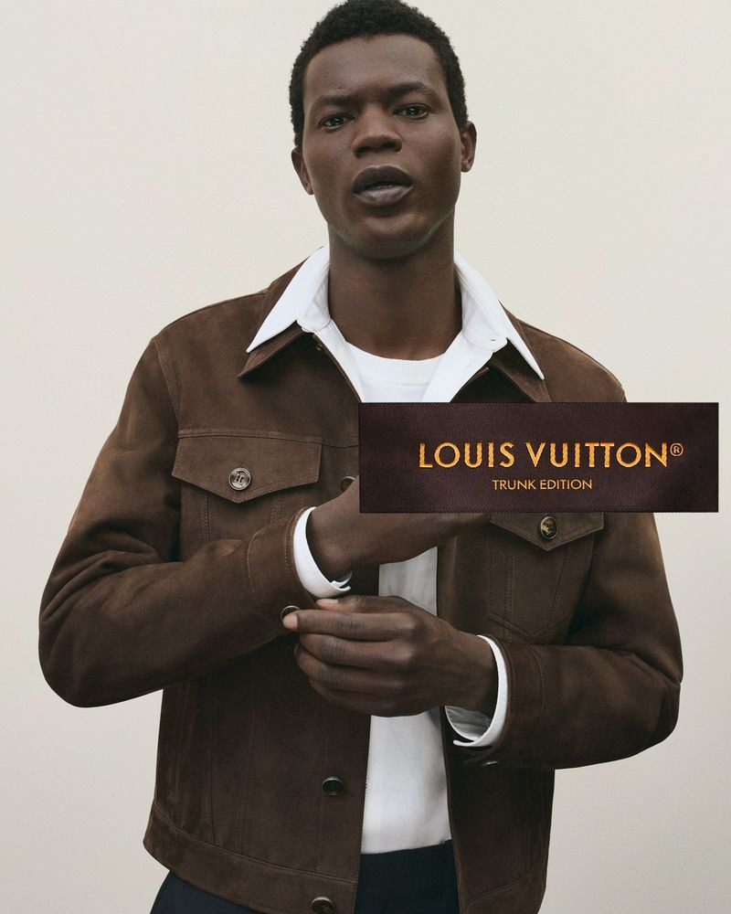 Mohammed wears a brown nubuck trucker jacket over a layered white t-shirt and white collared shirt, with a Louis Vuitton Trunk Edition label across the frame
