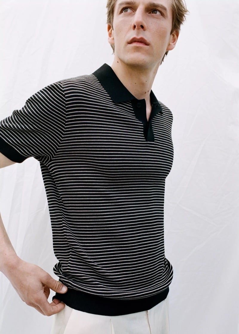 Side angle of Quentin in a Mango black and white striped knit polo with cream trousers