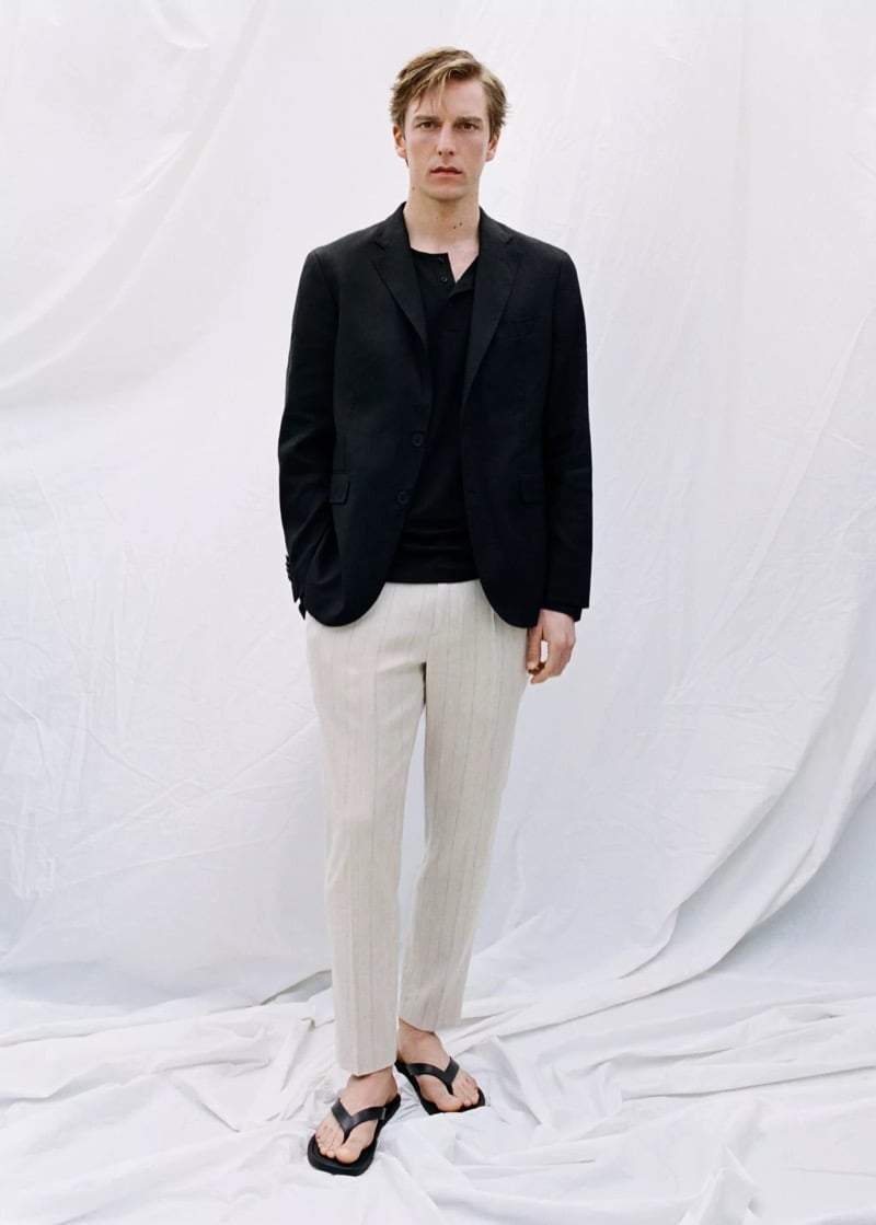 Quentin wears a Mango black linen blazer over a black polo with cream pinstriped trousers and black thong sandals