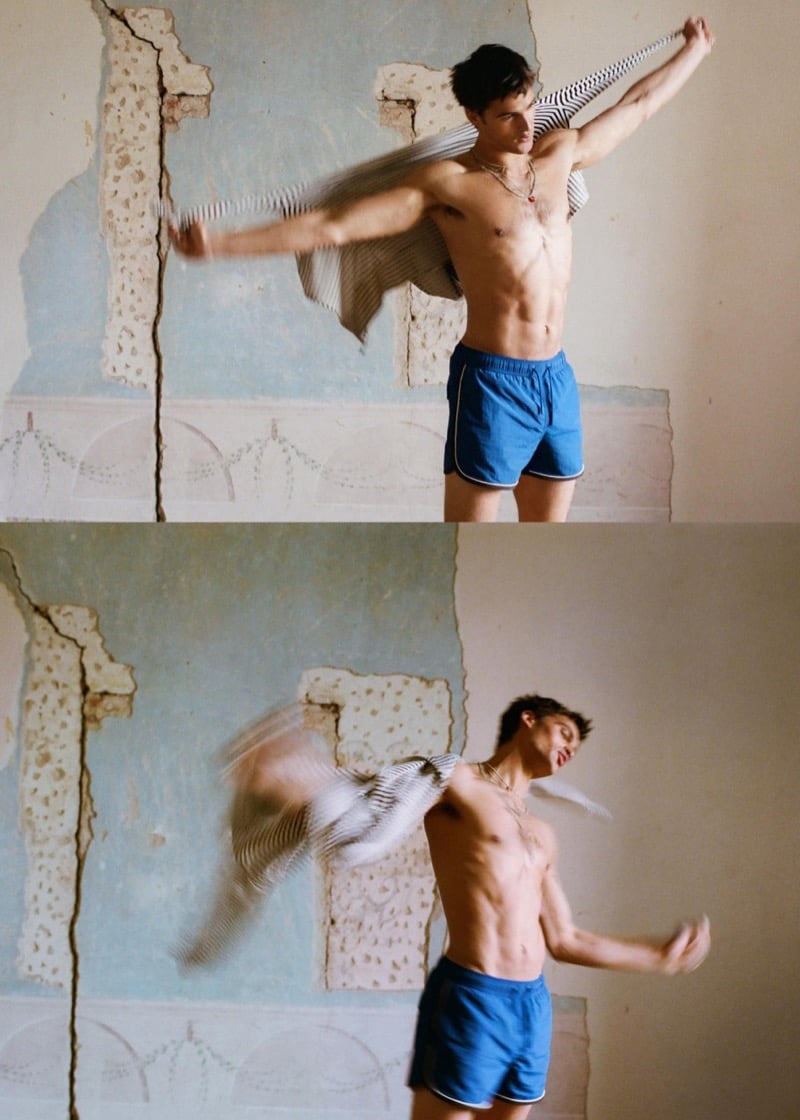 Parker tosses a striped shirt in motion while wearing blue swim shorts in front of a cracked fresco wall for Zara