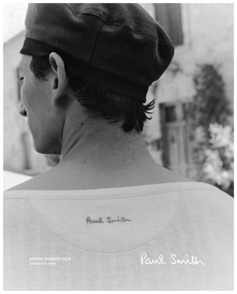 Back-view crop of Thibaud in a burgundy corduroy newsboy cap and a fine-ribbed knit top embroidered with the Paul Smith signature across the upper back