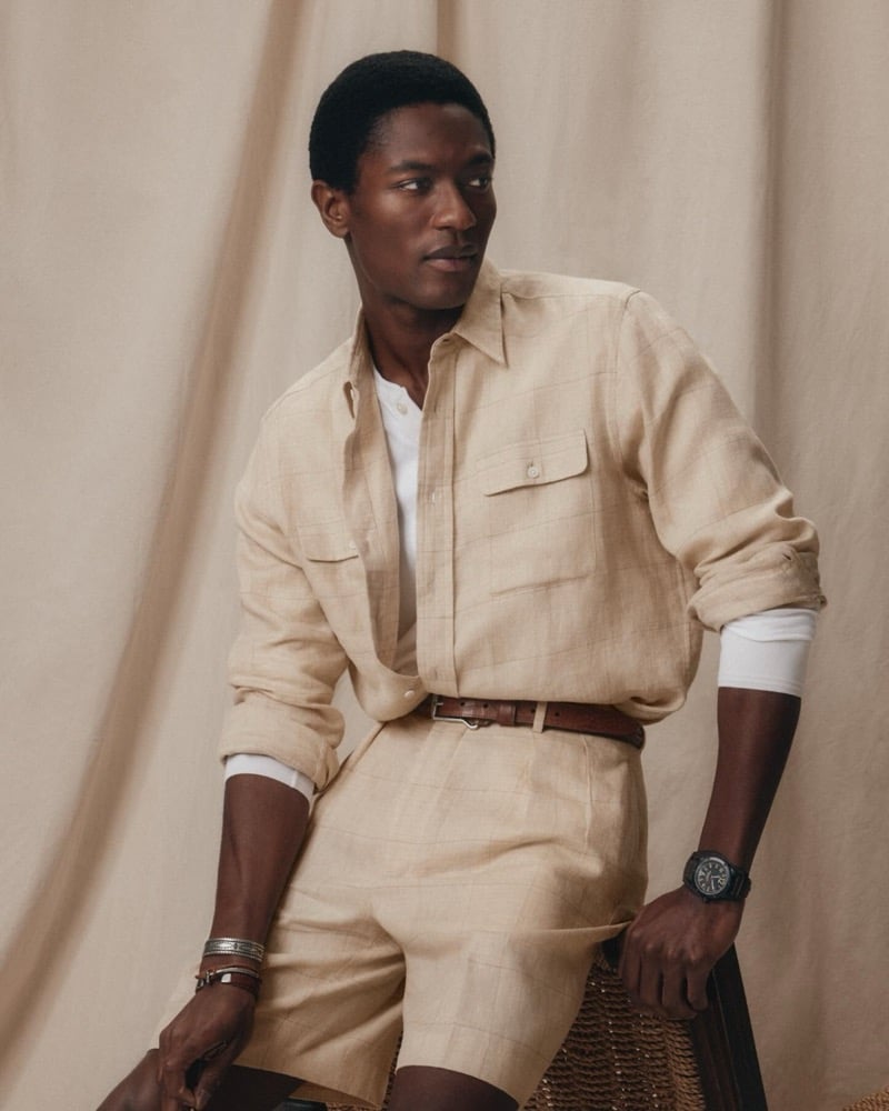 Hamid wears a sand-checked linen overshirt with patch pockets over a white tee with matching shorts and a Western leather belt