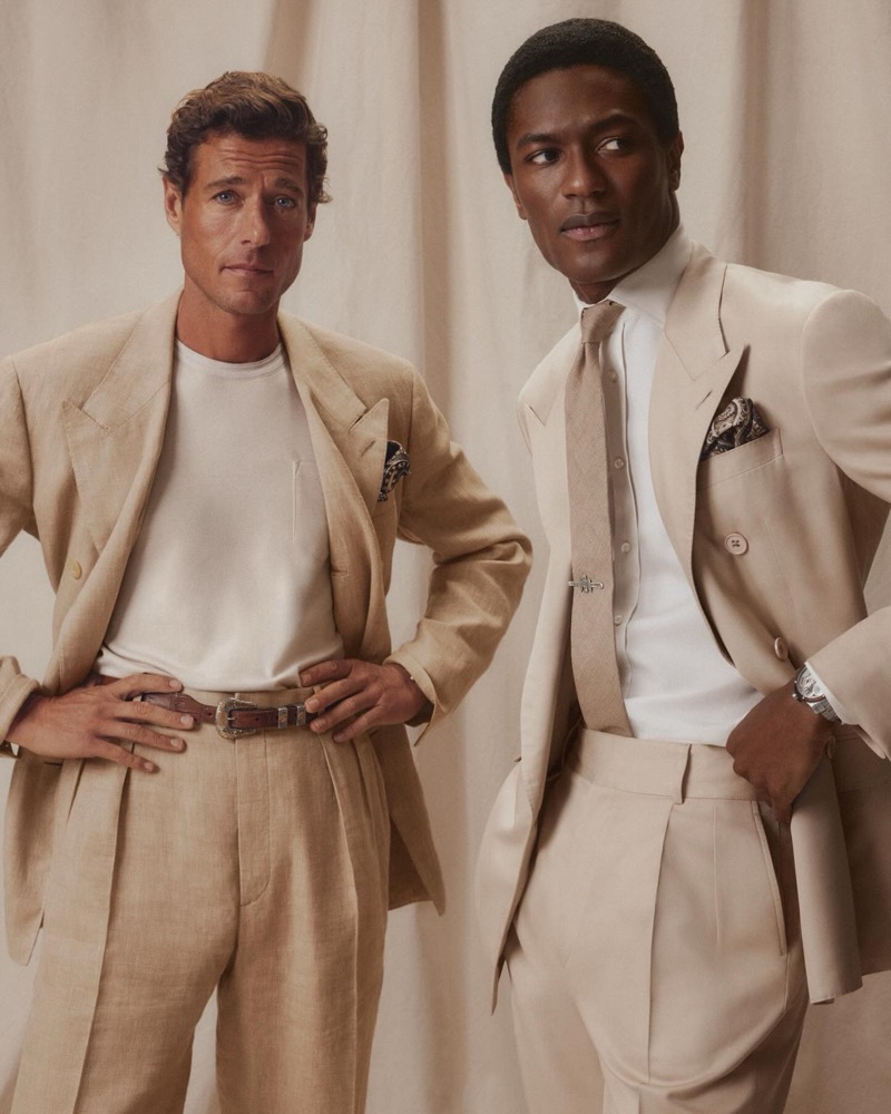Jon Paul in a tan double-breasted suit with a white tee stands beside Hamid in a champagne double-breasted suit with a tan tie and paisley pocket square