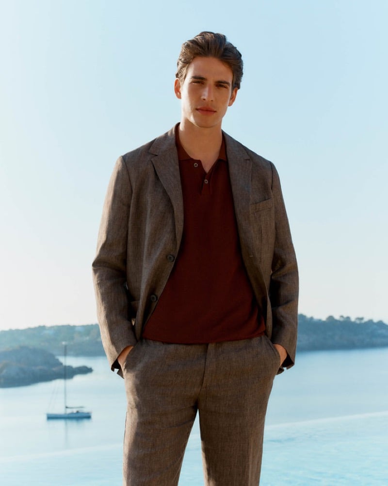 Amerigo stands by a seaside infinity pool in a brown linen suit worn with a garnet red knit polo shirt