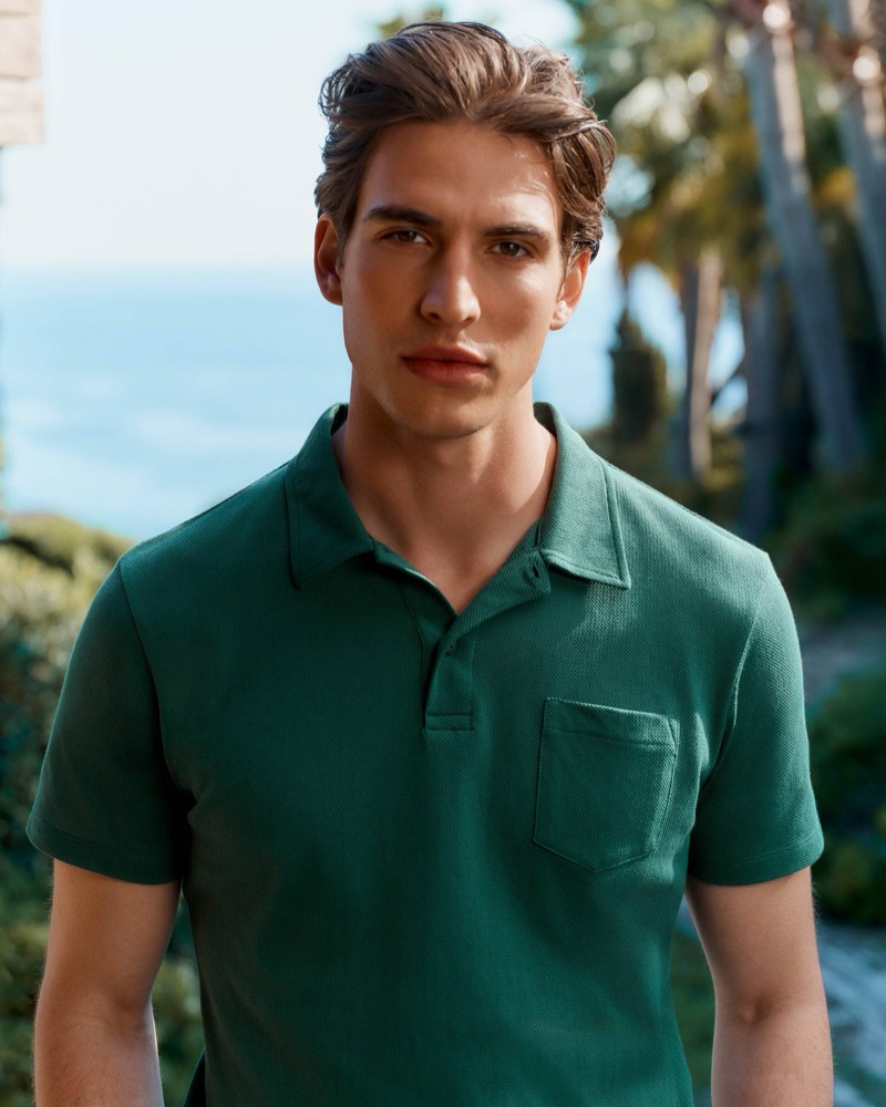 Amerigo stands among coastal greenery in a thyme green Riviera polo shirt with a chest pocket
