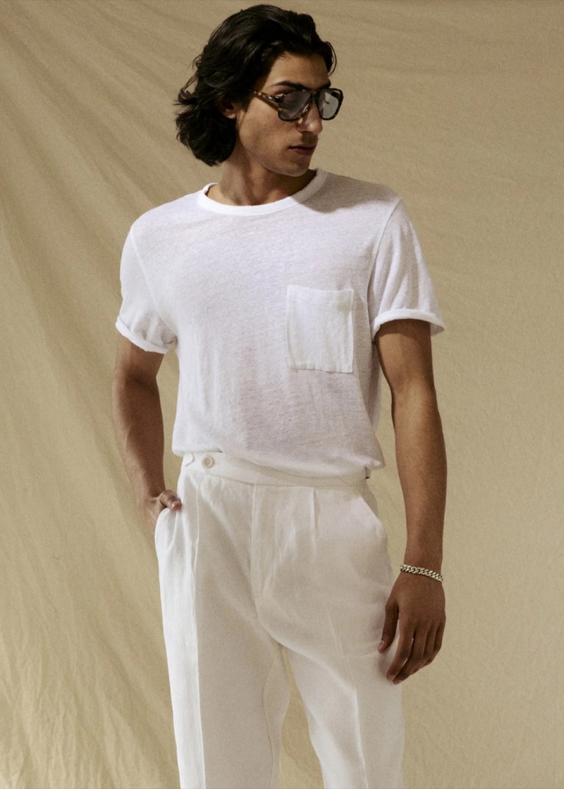 Adarsh wears a Todd Snyder short-sleeve white linen pocket tee with white pleated linen trousers, tortoise sunglasses, and a silver chain bracelet