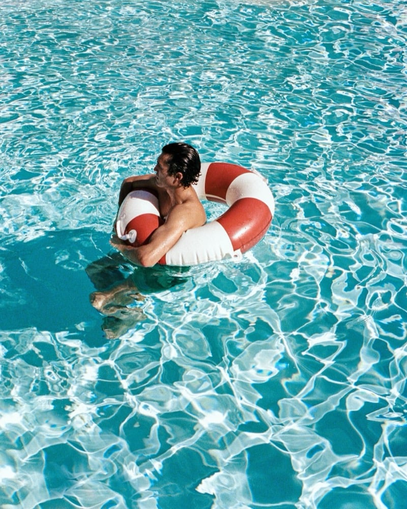 Overhead view of Francisco Henriques floating at the center of a turquoise pool inside a red and white life buoy, water rippling around him