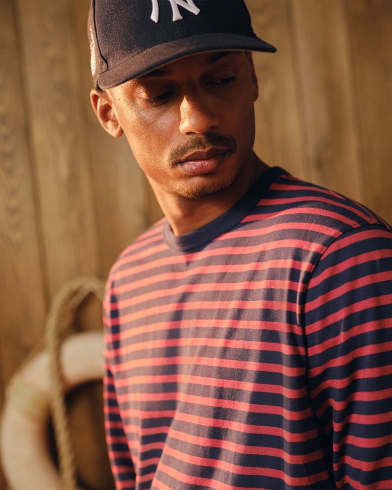 Close portrait of Ysham Jackson in a navy New York Yankees cap and a red and navy striped Abercrombie & Fitch long sleeve tee, head tilted down