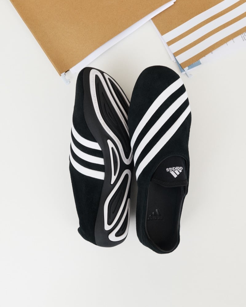 Adidas Originals Pharrell Williams Virginia Vario Flat Earther in black suede photographed from above with one pair flipped to reveal the sculptural rubber outsole