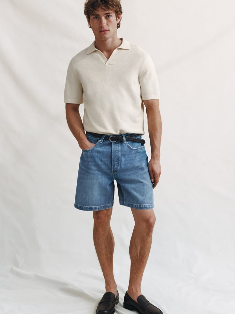 Valentin Humbroich wears a cream waffle-knit short-sleeve polo with mid-wash denim shorts, a braided brown belt, and dark brown leather loafers against a soft pale backdrop