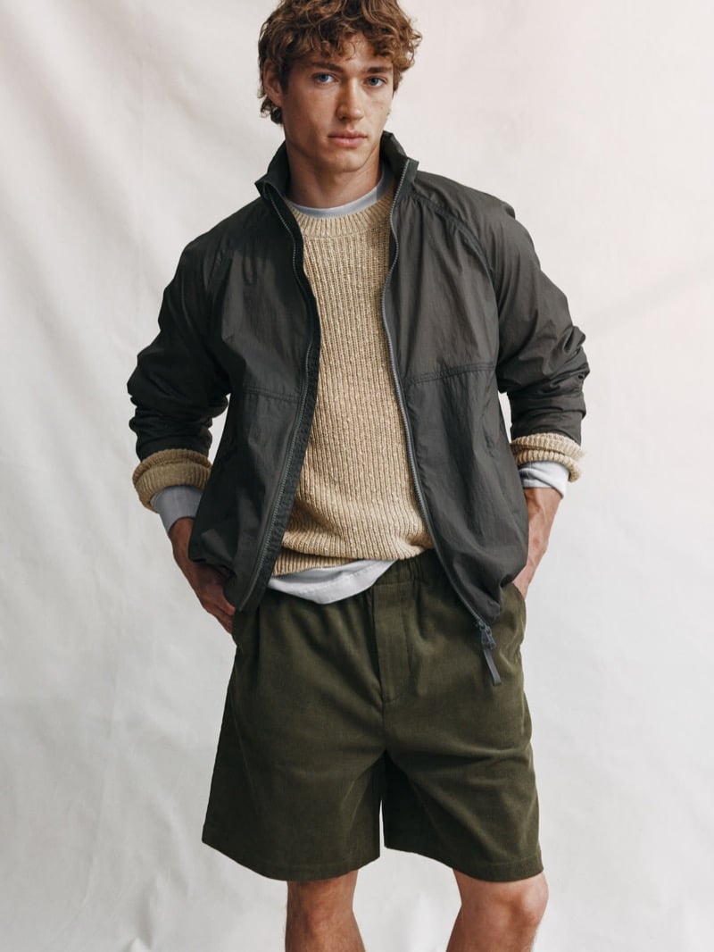 Valentin Humbroich wears a dark gray-green nylon jacket over an oatmeal chunky knit crewneck, finished with olive shorts