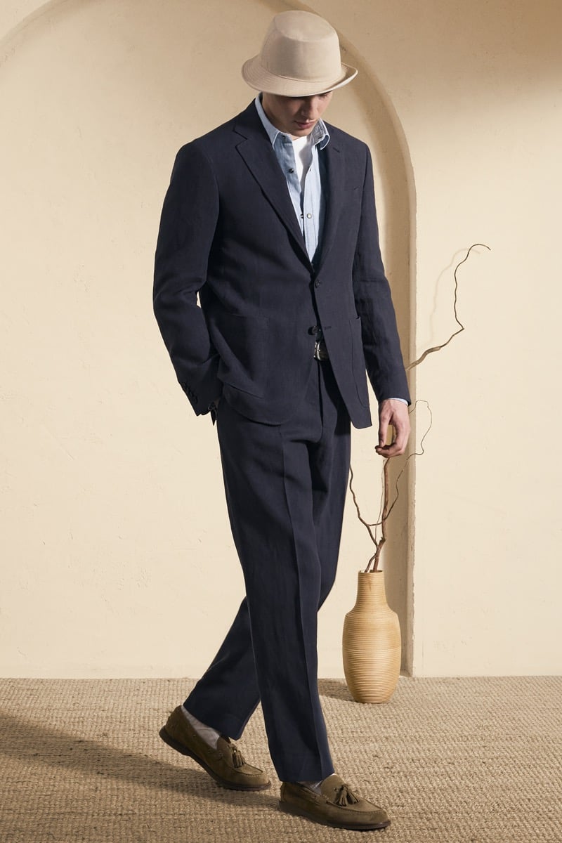 Model Peter Meyer in a cream panama trilby wears a navy linen suit over a light blue chambray shirt, finished with olive suede tassel loafers