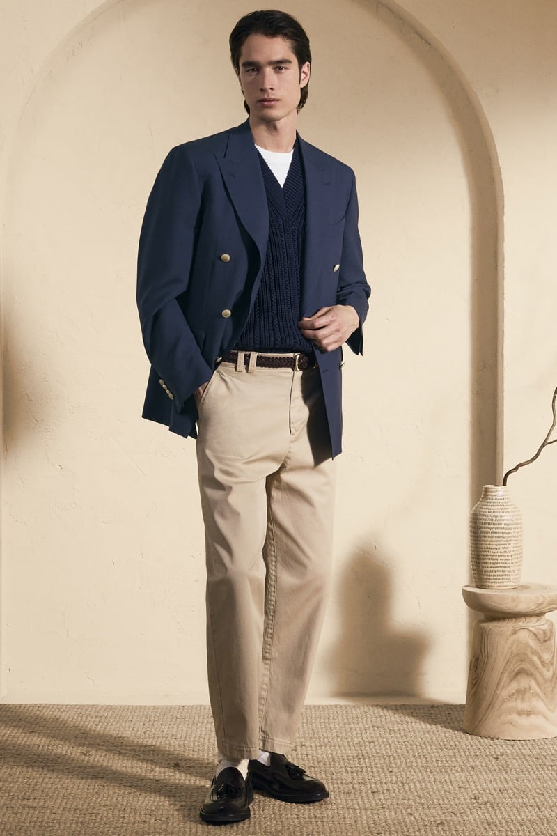 Model Peter Meyer in a navy double-breasted blazer with gold buttons over a navy openwork cable-knit V-neck and white tee, paired with stone wide-leg trousers and dark brown tassel loafers