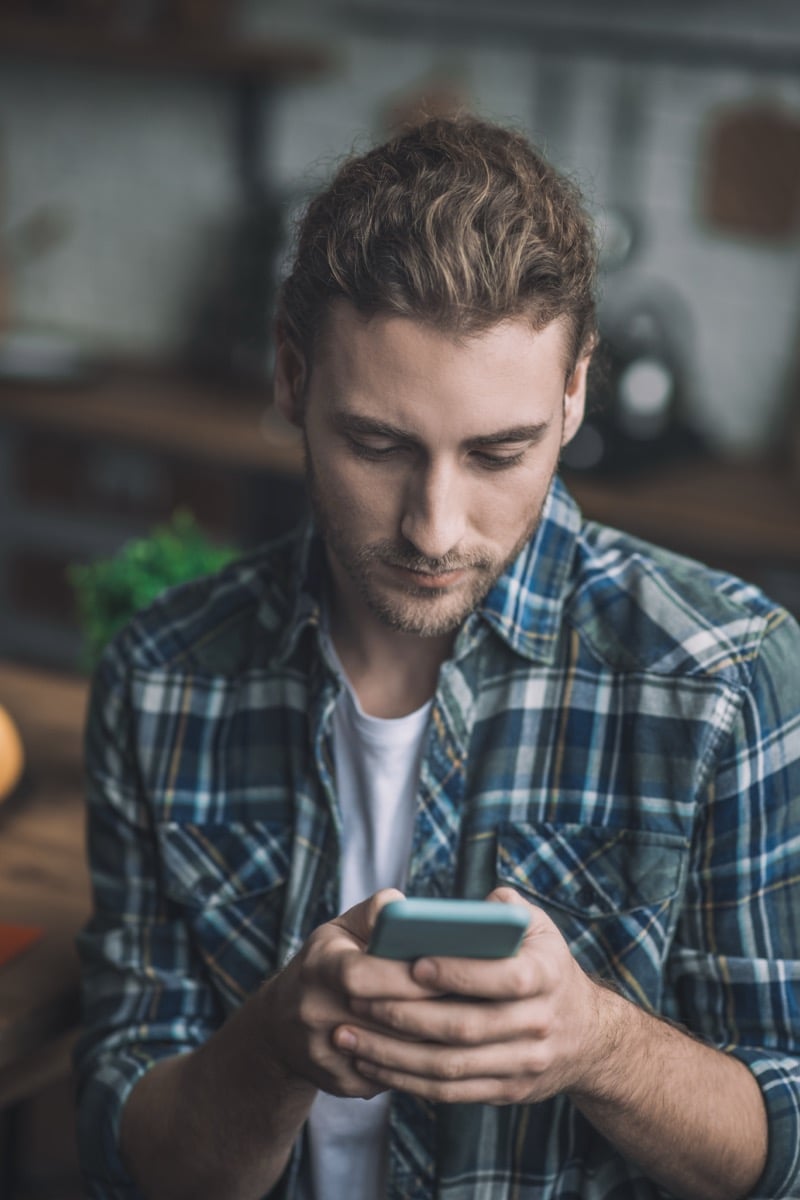 Young man concentrating on his smartphone screen, illustrating cross-device tracking and the online behavior retailers monitor