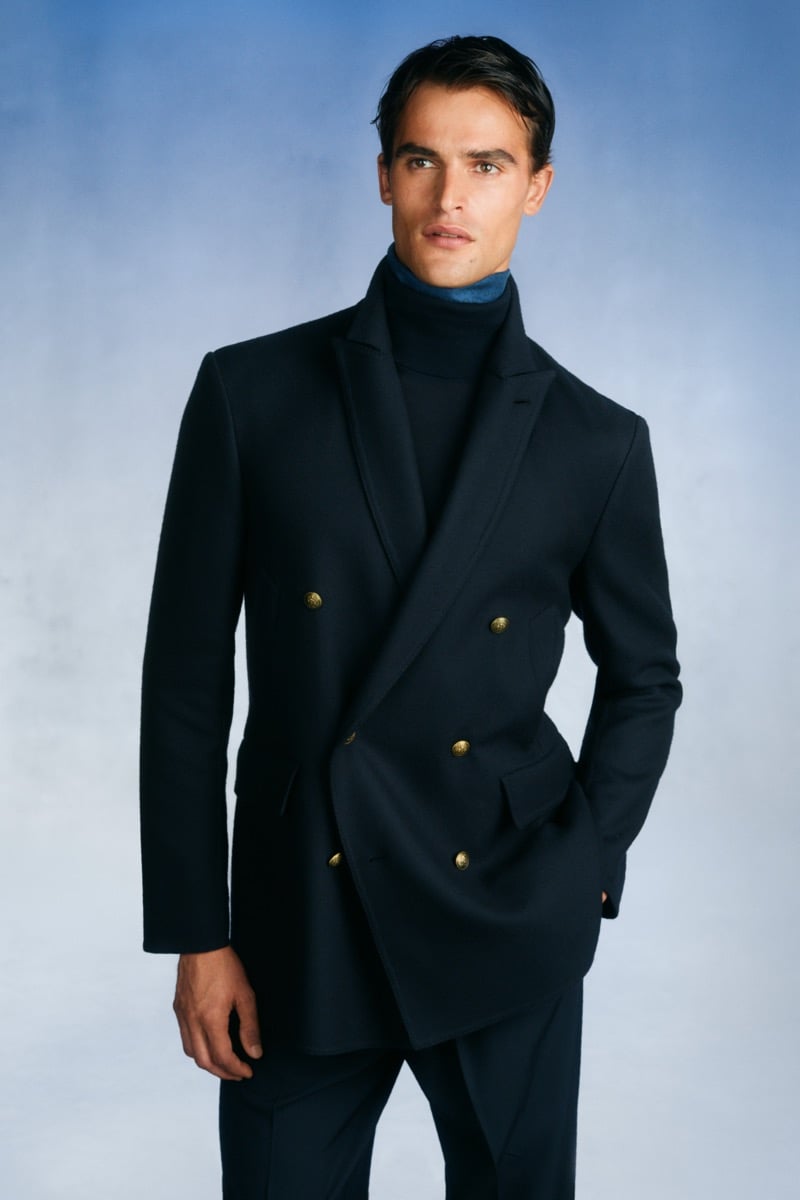 Model Parker Van Noord in a navy double-breasted suit with gold buttons over a navy turtleneck and slate blue silk scarf
