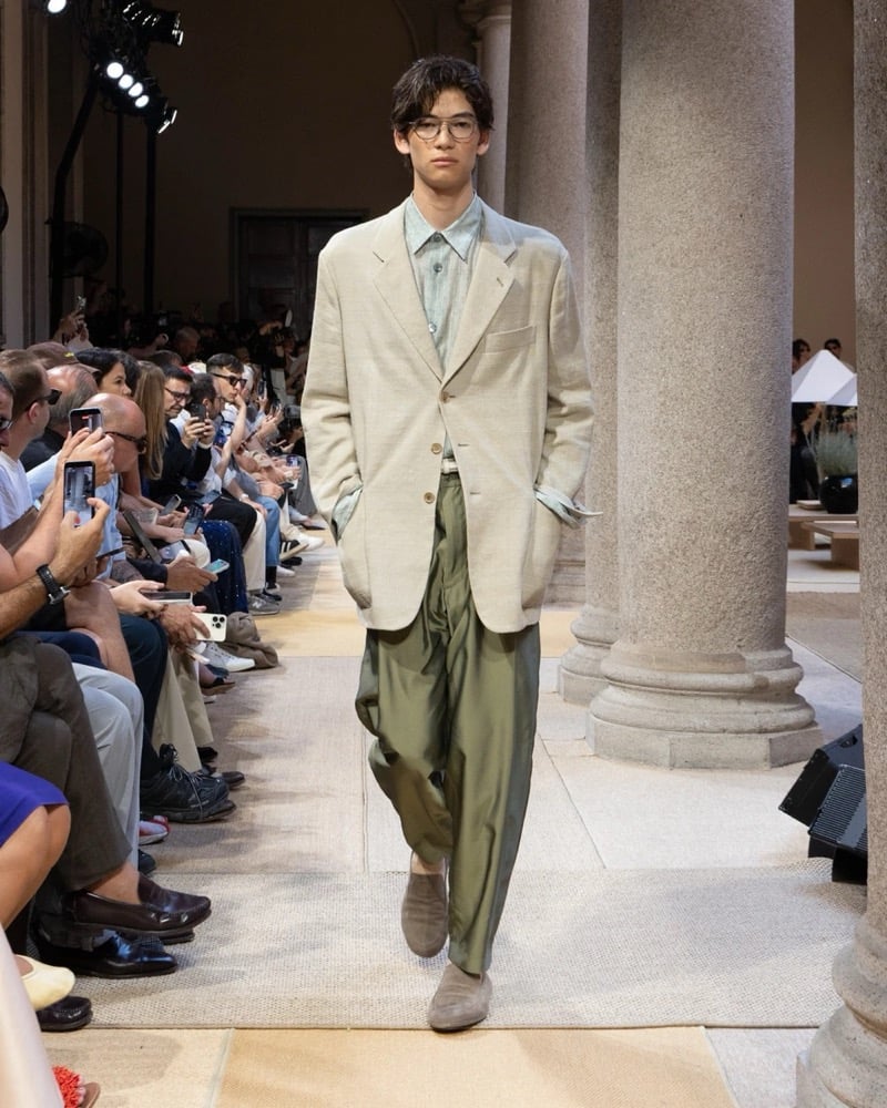 Model wears an oversized single-breasted linen blazer with a chest welt pocket, layered over an open camp-collar shirt and a tank with wide drapey trousers