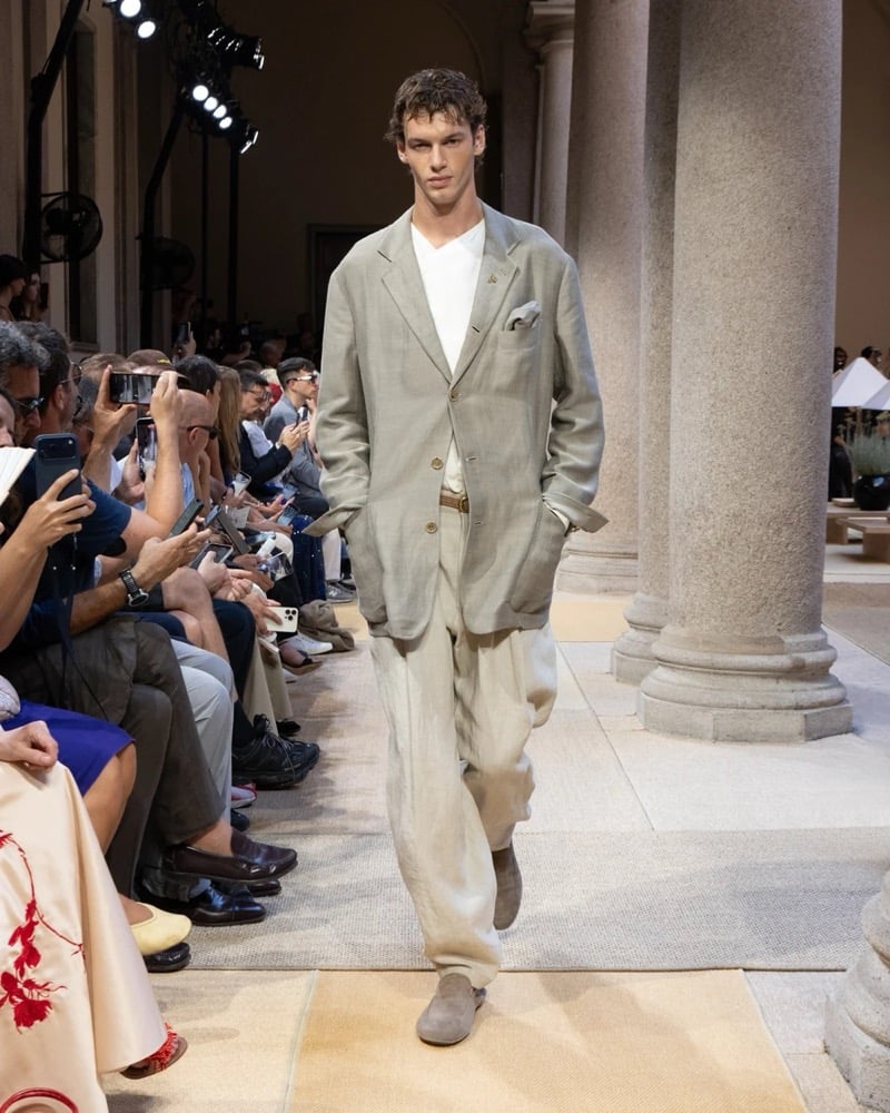 Model wears an oversized single-breasted linen blazer with notch lapels and patch pockets, layered over a soft tee with wide pleated linen trousers